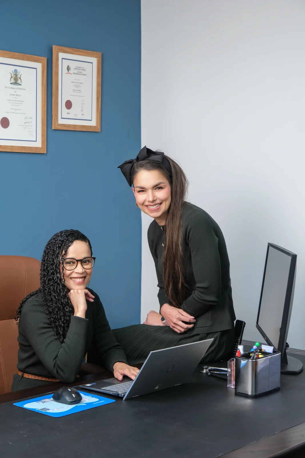 Two HERoeS HOME team members smiling together at a desk